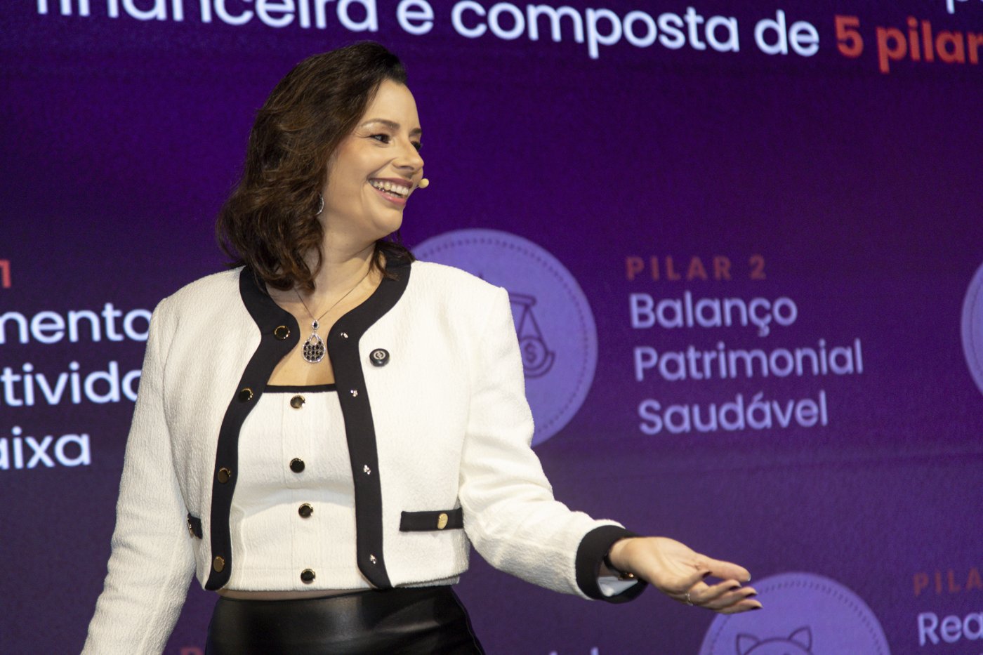 Lisa Dossi palestrando no palco sobre os pilares da vida financeira